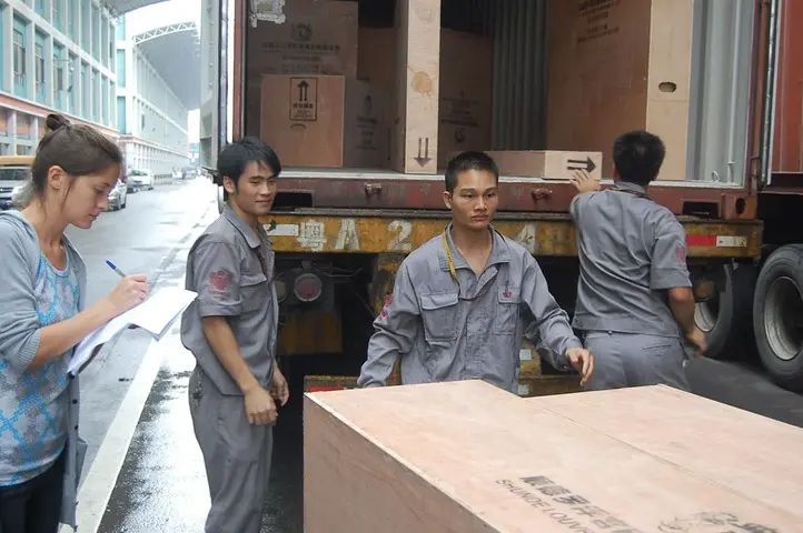 Работники загружают товары из Китая в контейнер на порту, организуя и закрепляя коробки для безопасной перевозки.